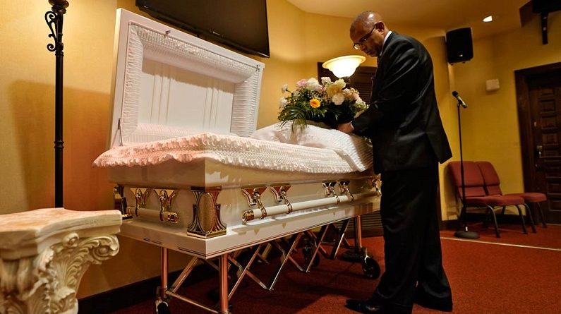 Associated Press | El director de la funeraria arregla flores en un ataúd antes de un servicio